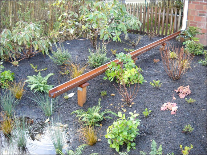 This elegant cedar trough adds a unique water feature to the rain garden.